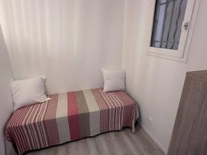 a small bedroom with a bed with a striped blanket at Appartement T2 avec piscine et vue mer proche plages - FR-1-768-76 in Les Issambres +6 photos