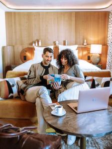a man and woman sitting on a bed with a laptop at Pullman Lyon in Lyon