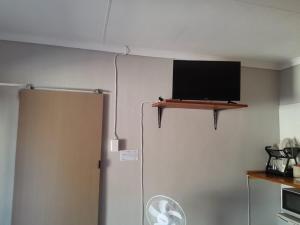 Elle comprend une télévision à écran plat sur un mur au-dessus d'un réfrigérateur. dans l'établissement Sweet Dreams Polokwane, à Polokwane