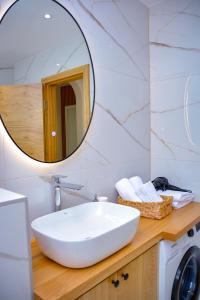 een badkamer met een witte wastafel en een spiegel bij Apartman Mona in Teslić