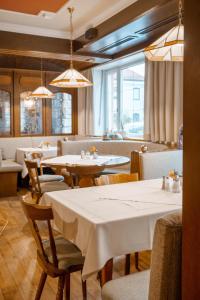 a restaurant with white tables and chairs and windows at Bavaria Lifestyle Hotel in Altötting