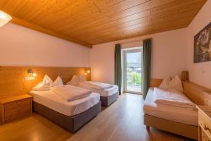 a hotel room with two beds and a window at Hotel Dolomiten in Dobbiaco