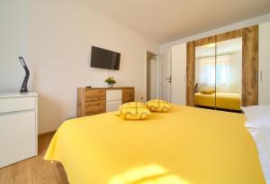 Una cama amarilla con dos almohadas amarillas encima. en Apartman Meri en Krk