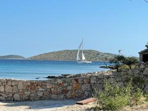 a sail boat in the water behind a stone wall at Kornati Robinson tourism in Kornati
