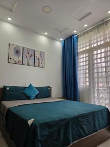 um quarto com uma cama com lençóis azuis e uma janela em VANAPARTMENT em Ho Chi Minh