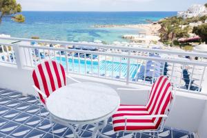 サンタ・エウラリア・デス・リウにあるHotel Mongibello Ibizaのビーチ付きのバルコニー(椅子2脚、テーブル1台付)