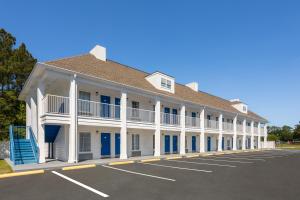 un gran edificio blanco con puertas azules y aparcamiento en Baymont by Wyndham Brunswick GA, en Brunswick