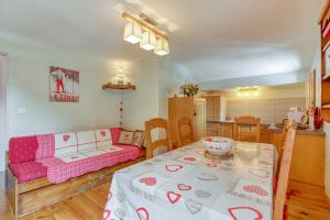 ein Wohnzimmer mit einem Tisch und einer rosa Couch in der Unterkunft Les Clarines - 3 chambres et jardin - magnifique vue in La Giettaz