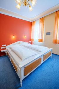 a large bed in a room with a red wall at Hotel Plankl in Altötting