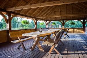 a wooden picnic table and benches on a wooden deck at Gościniec Figlówka in Laskowice