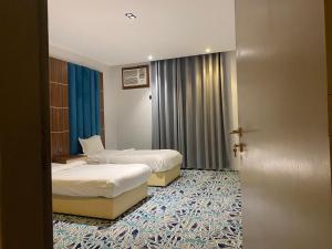 une chambre d'hôtel avec 2 lits et une porte dans l'établissement كيان ألين, à Abha