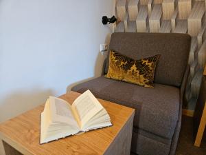 un libro abierto en una mesa junto a un sofá en Dei Hotel Schönblick en Velden am Wörthersee