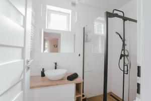 uma casa de banho branca com um lavatório e um chuveiro em Leśne zacisze - dom z kominkiem i balią em Jordanów