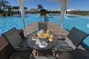 a table with food and drinks next to a swimming pool at Arapey Thermal All Inclusive Resort & Spa in Termas del Arapey