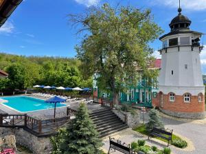 a building with a lighthouse next to a pool at Mayak Resort in Kam”yani Potoky