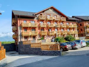 a large building with wooden balconies and cars parked in a parking lot at Tatry PANORAMA apartmány Tatragolf B-F in Veľká Lomnica