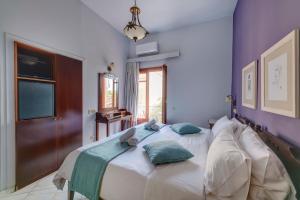 1 dormitorio con 1 cama con sábanas blancas y almohadas verdes en Electra Syros - Adults Only, en Ermoupoli