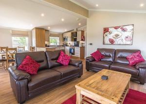 a living room with a leather couch and a table at Woodhall Country Park Lodges in Woodhall Spa
