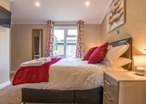 a bedroom with a large bed with red pillows at Woodhall Country Park Lodges in Woodhall Spa