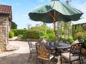 Hayden Farm في Culmstock: طاولة مع مظلة خضراء على الفناء
