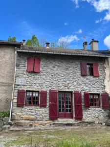 an old stone house with red shuttered windows at La Régalade, Pyrénées in Sorgeat