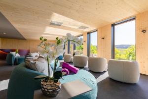 ein Wohnzimmer mit einem Sofa, Stühlen und Fenstern in der Unterkunft FAIR RESORT All Inclusive Wellness & Spa Hotel Jena in Jena