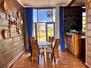 una sala da pranzo con tavolo, sedie e finestra di Amboseli Glass house a Oloitokitok 