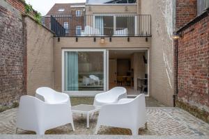 a patio with white chairs and a table and a balcony at Meningate Lodge in Ieper