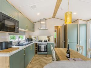Brigham的住宿－Seren，厨房配有绿色橱柜和木桌