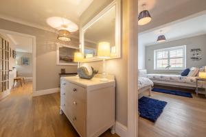 a bedroom with a bed and a dresser with a mirror at Spring Cottage in Burnham Market