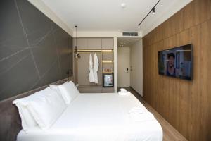 a bedroom with a large white bed and a tv at Charm Hotel in Vlorë