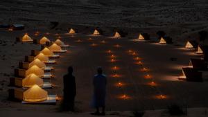 Al WāşilAdventurer Camp的两个男人在夜晚站在沙漠中