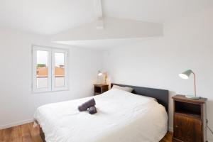 1 dormitorio con 1 cama blanca y ventana en Appartement climatisé 2 chambres en Villefranche-sur-Saône