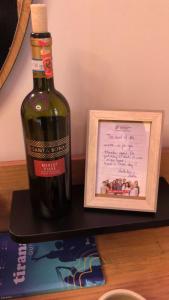 una botella de vino sentada junto a una foto enmarcada en Deluxe Apartment In City Center en Tirana
