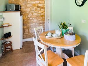 eine Küche mit einem Holztisch mit Stühlen und einem Kühlschrank in der Unterkunft Rose Cottage in Chipping Campden