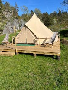 里瑟尔Hommen Gård Glamping的田野里的两张躺椅和一顶帐篷