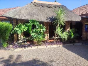 un edificio con una cabaña de paja con palmeras en Ditshane Lodge, en Gaborone 4 fotos más