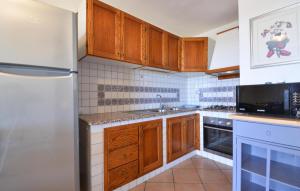 a kitchen with wooden cabinets and a refrigerator at Secca in Costa Rei