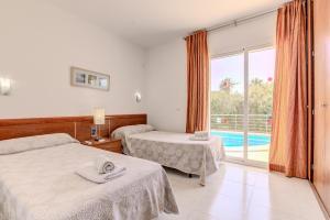 a hotel room with two beds and a pool at Villa Vistafar by Rentallorca in Alcudia