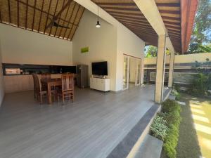 a dining room and living room with a table and a television at Anugerah Villa 3 in Amed