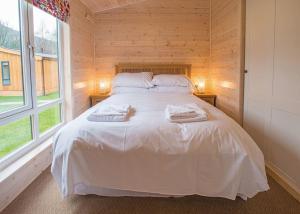 a bedroom with a white bed with two towels on it at Dovestone Holiday Park in Greenfield
