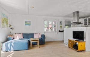 2 Bedroom Amazing Home In Thyholm في Thyholm: غرفة معيشة مع أريكة زرقاء وتلفزيون
