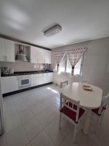 a kitchen with a white table and a table and chairs at Piso da Playa in Laxe