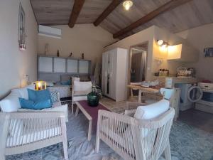 a living room with white furniture and a kitchen at La cabane d'Alcée in Vacqueyras