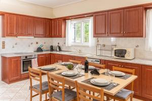 a kitchen with wooden cabinets and a table with chairs at Arte villa Margarita apartment in Karavomylos