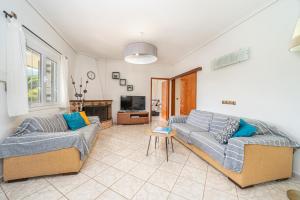 a living room with two couches and a tv at Arte villa Margarita apartment in Karavomylos