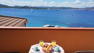 stolik z 2 kieliszkami soku pomarańczowego i widokiem na ocean w obiekcie Appartamentino panoramico...con finestra sul mare! w mieście La Maddalena