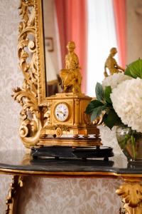 Grand Hotel Villa Serbelloni - A Legendary Hotel في بيلاجيو: ساعة ذهبية على طاولة بها إناء من الزهور
