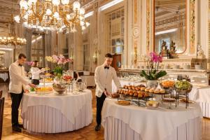 Grand Hotel Villa Serbelloni - A Legendary Hotel في بيلاجيو: مجموعة من الرجال واقفين أمام الطاولات مع الطعام