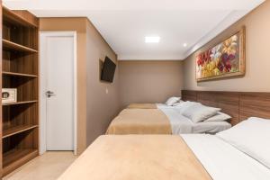 a bedroom with two beds and a tv at VilaHotell Recife in Recife